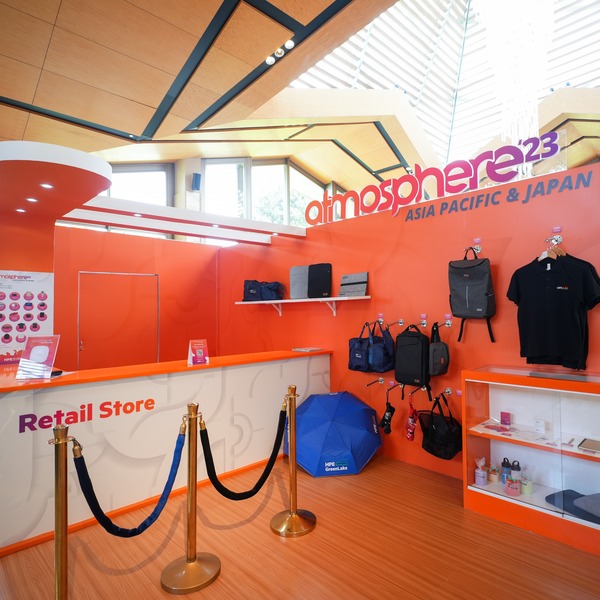 A vibrant orange wall with Atmosphere '23 merchandise on display.